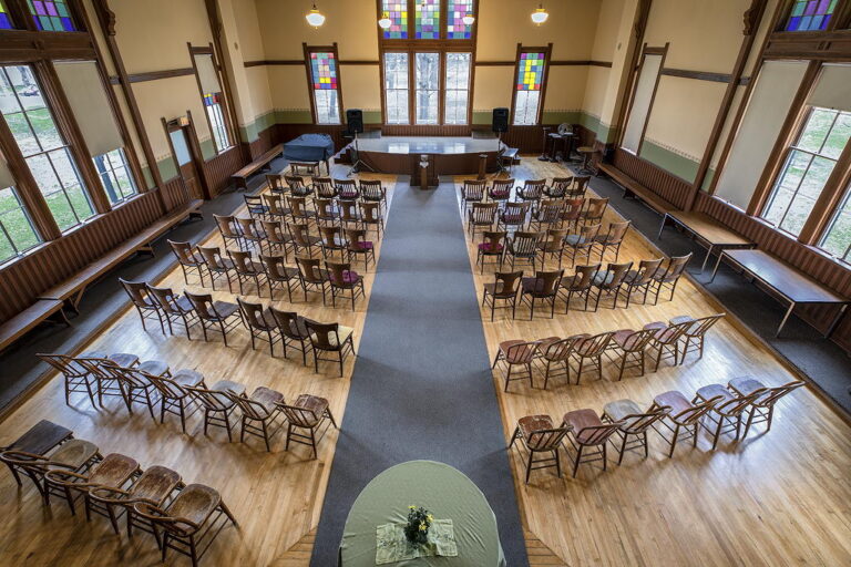 A spacious room filled with numerous chairs and tables arranged for an event or gathering.