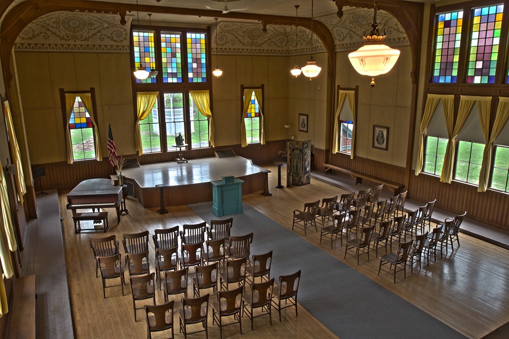 A spacious room filled with numerous chairs and a grand piano positioned prominently in the center.
